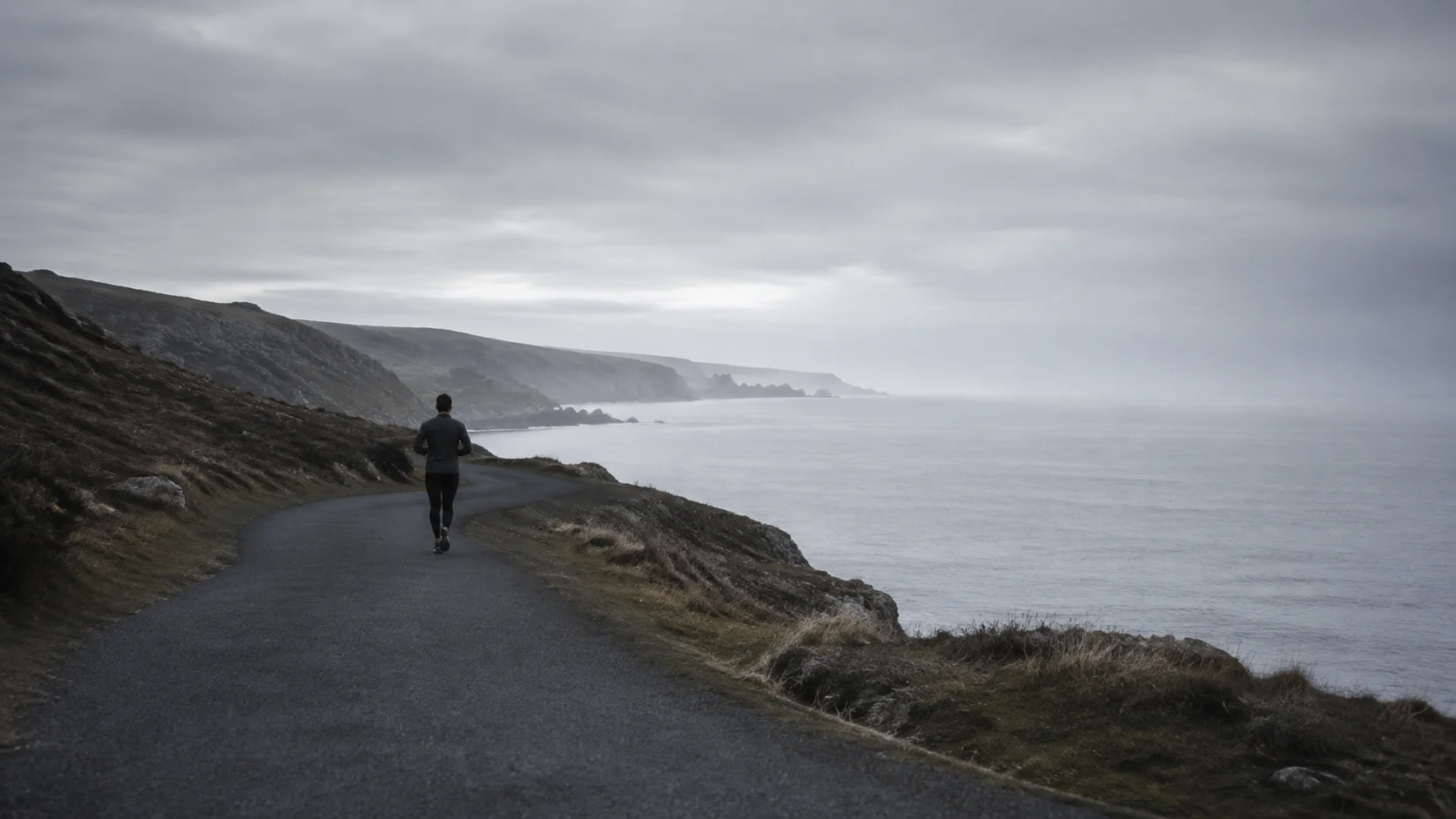 A lone runner following a quiet coastal path in the cool morning light